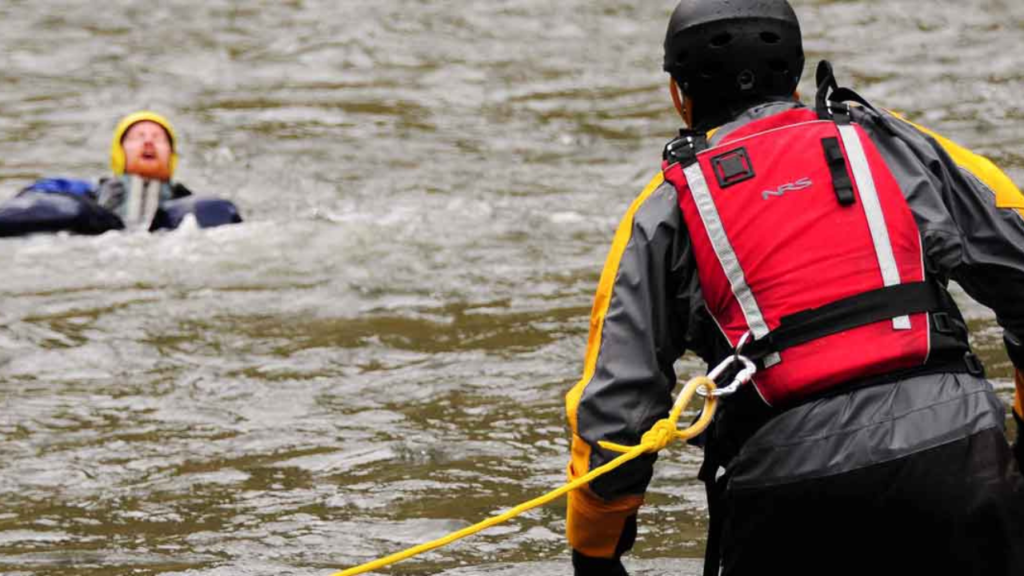 Rescate acuático: rescatista en sector derecho de la imagen, preparado para ayudar a persona que está flotando en el río, al costado izquierdo de la imagen